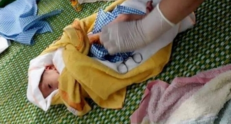 Bé trai sơ sinh trong túi nilon treo trên xe máy bên đường