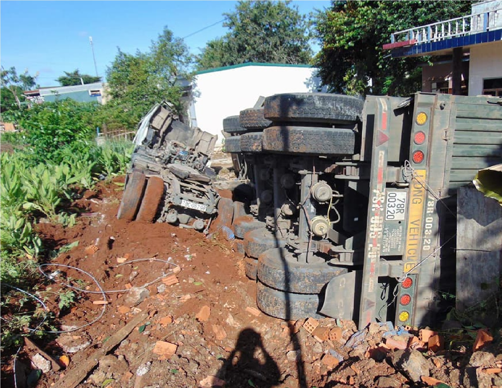 Tránh xe tải, xe Container “bay” vào nhà dân nằm lật ngang